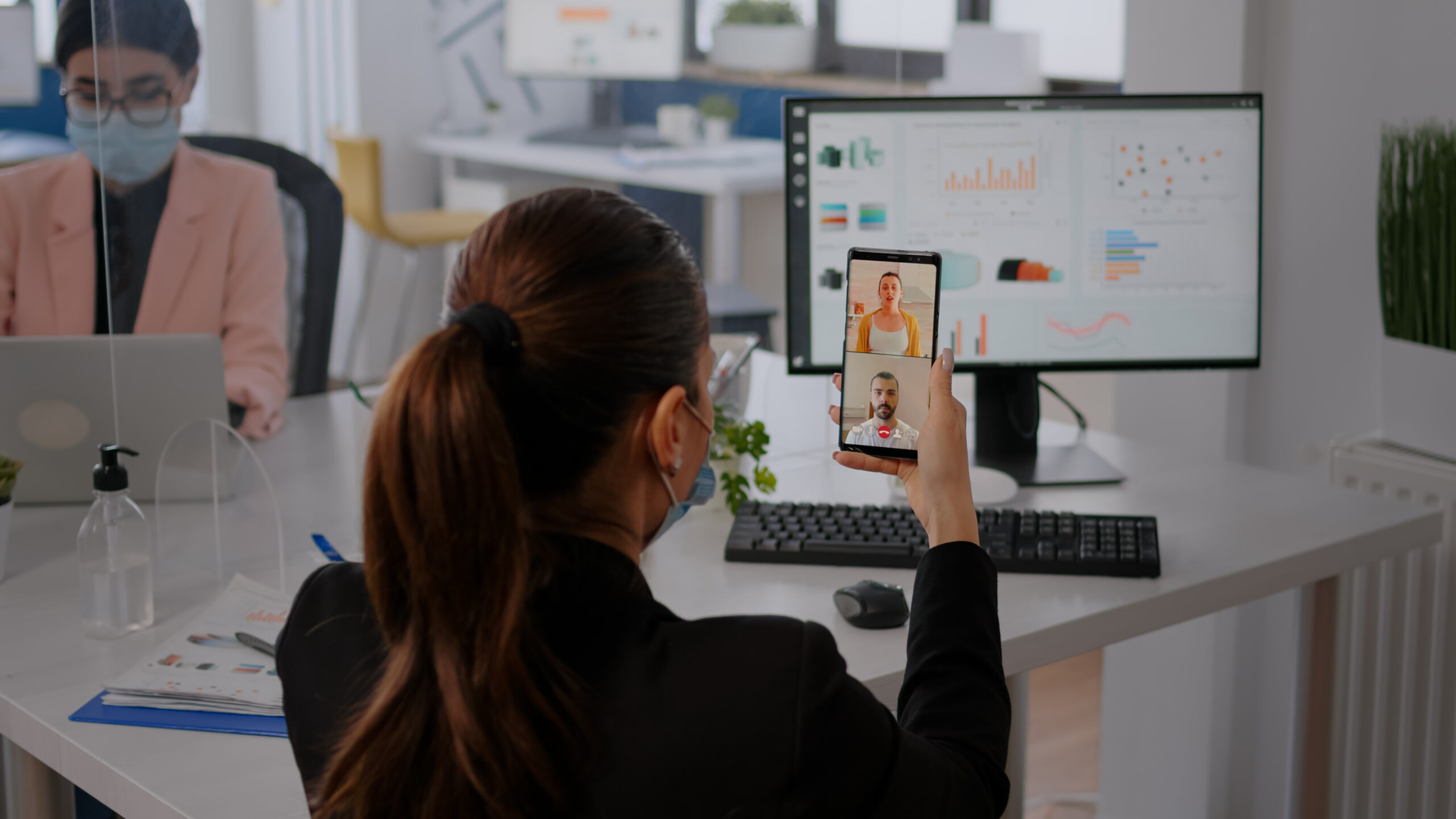 Executive business woman wearing protective face mask using phone for online videocall conference