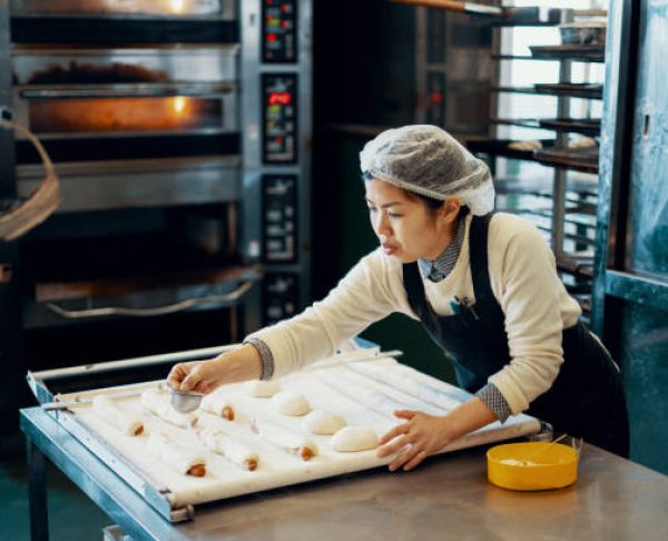 Mid adult woman baking bread in an industrial kitchen in Japan