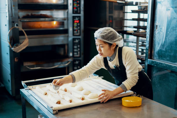 Mid adult woman baking bread in an industrial kitchen in Japan